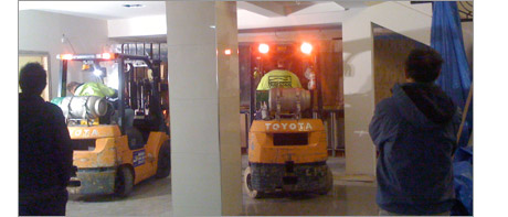 2 fork lift trucks inch a 5m acrylic aquarium through a hotel reception and onto a teel support structure.